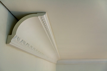 Close-up detail of decoration white molding connected with glue adhesive to wall and ceiling in...