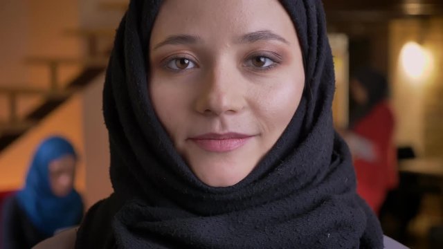 Closeup portrait of young beautiful muslim female office worker in back hijab looking straight at camera with neutral facial expression