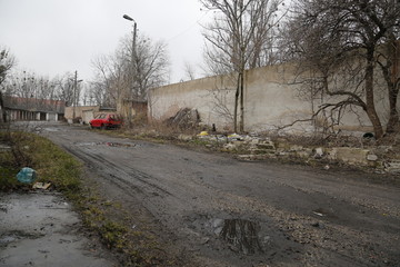 Old, neglected, ruined garages. Muddy, holey, uneven road with puddles. Winter, autumn landscape in the city. Wrocław, Wroclaw, Breslau. Lower Silesia, Dolny Śląsk. Polska, Poland, Polen