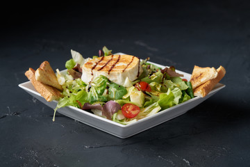 Fresh green healthy salad with grilled goat cheese chevre isolated on black background