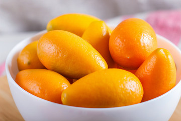 kumquats in a white plate on a white wooden background