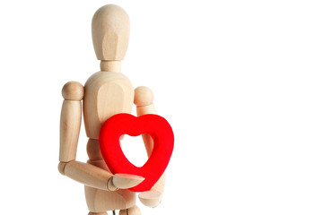 The wooden figure of a man holds in his hands a red heart on a white background. Gives the heart