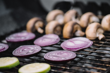 Obraz na płótnie Canvas selective focus of raw onion slices, zucchini and mushrooms grilling on barbecue grill grade