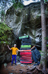 Rock climber demonstraiting a huge pile of crash pads used for protection