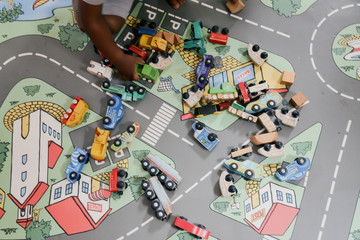 child playing with wooden toy cars on a carpet with streets