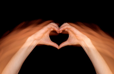 Fototapeta premium heart of hands in move on black background