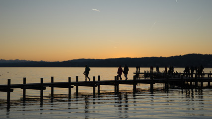 Fototapeta na wymiar Menschen auf dem Steg am Starnberger See bei Sonnenuntergang