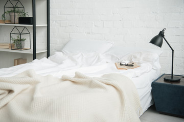 Fototapeta na wymiar Bedroom with rack, white bed and lamp on nightstand