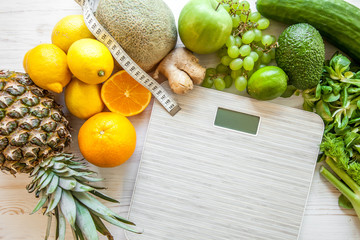 Flat lay composition with scales, healthy vegetables and fruit on wooden background. Weight loss...