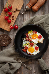 Pan with Fried eggs and cherry tomatoes on rustic background. Top view, close up, flatlay