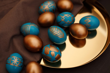 golden decorated easter eggs with golden tray on dark wooden background