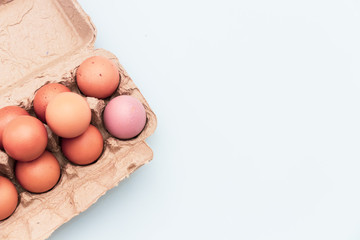 Closeup of raw chicken eggs in egg box on brown white background