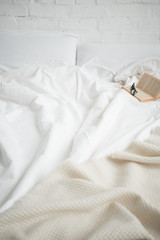 Fototapeta na wymiar book and glasses on empty cozy white bed