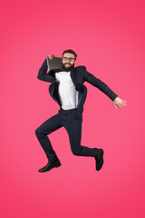 Fototapeta na wymiar Jumping man in suit holding laptop