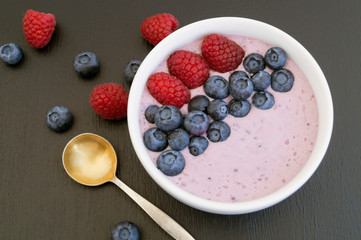 Blueberry yogurt with fresh berries on a wooden table.