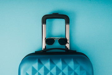 top view of sunglasses and travel bag on blue background