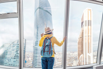 Obraz premium Cheerful young tourist girl at the observation point in modern skyscraper building