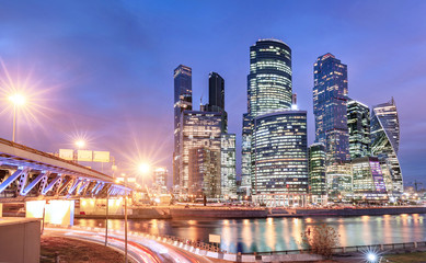 Fototapeta na wymiar Illuminated Skyscrapers in Moscow City or international business centre at night time with lights, view from water pond embankment with reflections