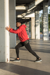 Black runner doing stretching exercise for warming up.