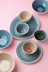 Beautiful blue, grey, beige dinnerware, plates bowls on pink table, top view, selective focus