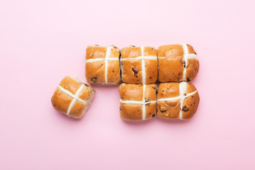 Six hot cross buns, traditional British Easter food on pink background, top view, selective focus