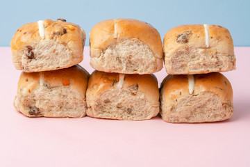 Six hot cross buns, traditional British Easter food on pink and blue background, selective focus