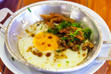 Traditional Thai Breakfast Cuisine, fried egg with sliced Chinese sausage and minced pork, seasoned with pepper and soy sauce, served on hot saucepan. Thailand Street Food, Asia Culture Travel concept