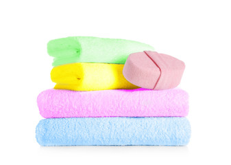 Stack of clean soft towels and sponge on white background