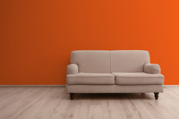 Comfortable sofa in room near orange wall. Space for text