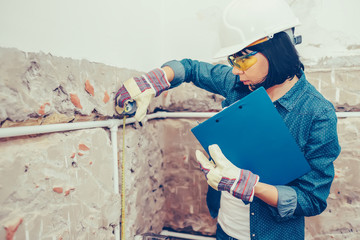 Female construction worker using measuring tape