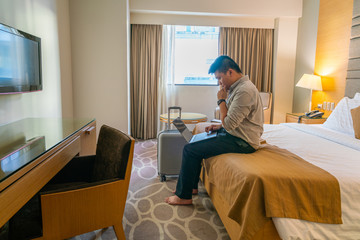 Asian businessman using laptop in hotel room