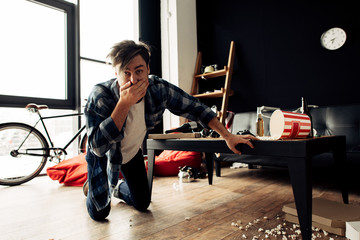 drunk man feeling nauseated while covering mouth at home after party