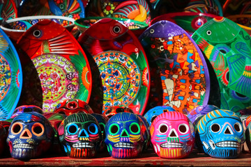 Traditional Mexican souvenirs. Multi-colored ceramic skulls and tableware in the gift shop. Symbol of the day of the dead. Selective focus.