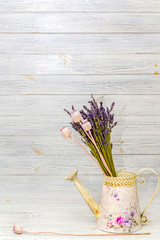 dried lavender and dried poppy in an iron watering can on a light wooden background. style - "shebbie chic". place for text