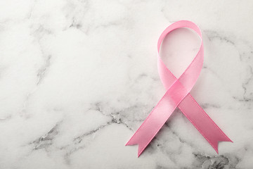 Pink ribbon on marble background, top view with space for text. Breast cancer awareness concept