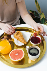 Obraz na płótnie Canvas French Breakfast with croissant and coffee. Women's hands break croissant. Coffee, jam, croissant, orange juice, grapefruit, lychee. Top view, white background
