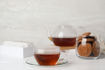 Cup of hot fresh tea and cookies on table against light background. Space for text