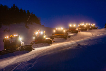 Fleet of snowcats grooming Spruce Peak at dusk, Stowe, Vermont, USA