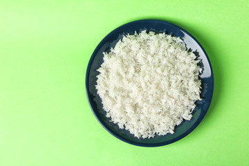 Plate of boiled rice on color background, top view with space for text