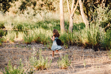 Young blonde girl running in the field wearing a dress