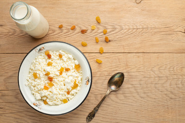 Cottage cheese with raisins and zucchini, with milk in a bowl on a wooden table. Diet, tasty and healthy food