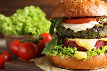 Vegan burger with beet and falafel patties on table against blurred background, closeup