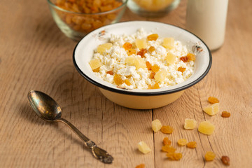 cottage cheese with raisins and pineapple zucchini, with milk in a bowl on a wooden table. Diet, tasty and healthy food