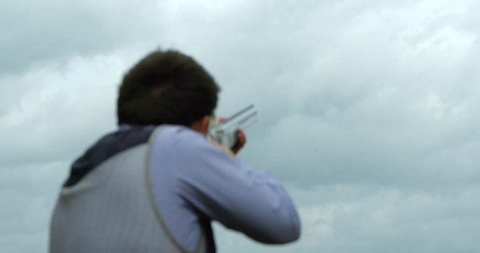 A Clay Pigeon shooter lines up the clay, pulls the trigger and hits the target in slow motion.
