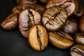 Brown roasted coffee beans on black background, close up, macro