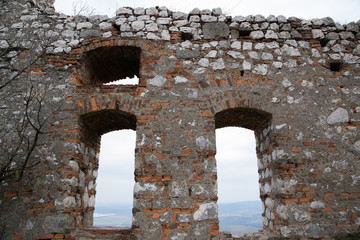 A view of the stony window of the old castle in the background is a village many miles away