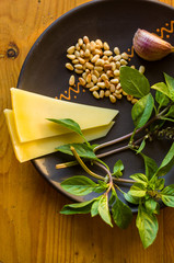 Fresh ingredients for preparing Italian pesto sauce - lemon basil sprigs, peeled seeds of cedar nuts, large garlic clove, Greek olive oil, Parmesan cheese