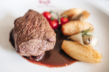 Plate of beef cooked with potatoes and fresh tomatoes