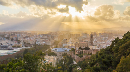 Obraz premium Ray of Light at sunset among the clouds in the city of Malaga