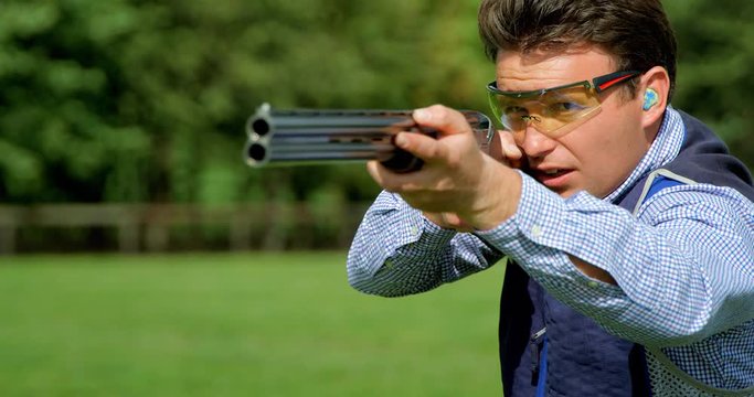 A clay Pigeon shooter swings past camera and pulls the trigger.